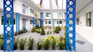 Une cour intérieure avec une fontaine centrale, entourée d’une variété de plantes et d’arbres.