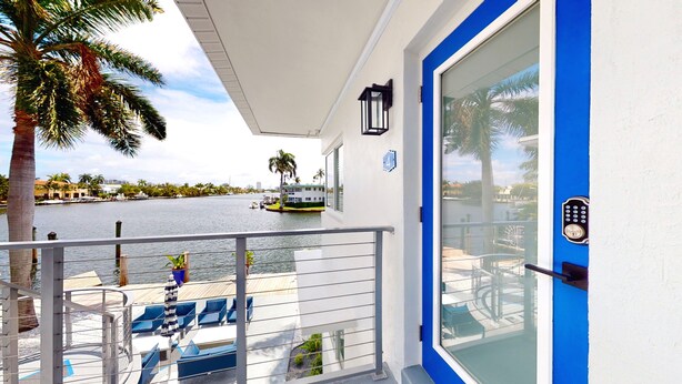 Un balcon avec vue sur une rivière, un bateau et des palmiers.