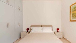 Un dormitorio con cama, dos mesitas de noche y un armario.