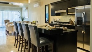 Une cuisine moderne dotée d’un îlot central, d’appareils électroménagers en acier inoxydable et d’un coin repas avec des chaises et une table.