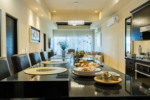 Enjoy meals in this stylish dining area with a long table and chandelier.