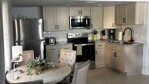 A modern kitchen with stainless steel appliances, a dining area with a table and chairs, and a ceiling fan.