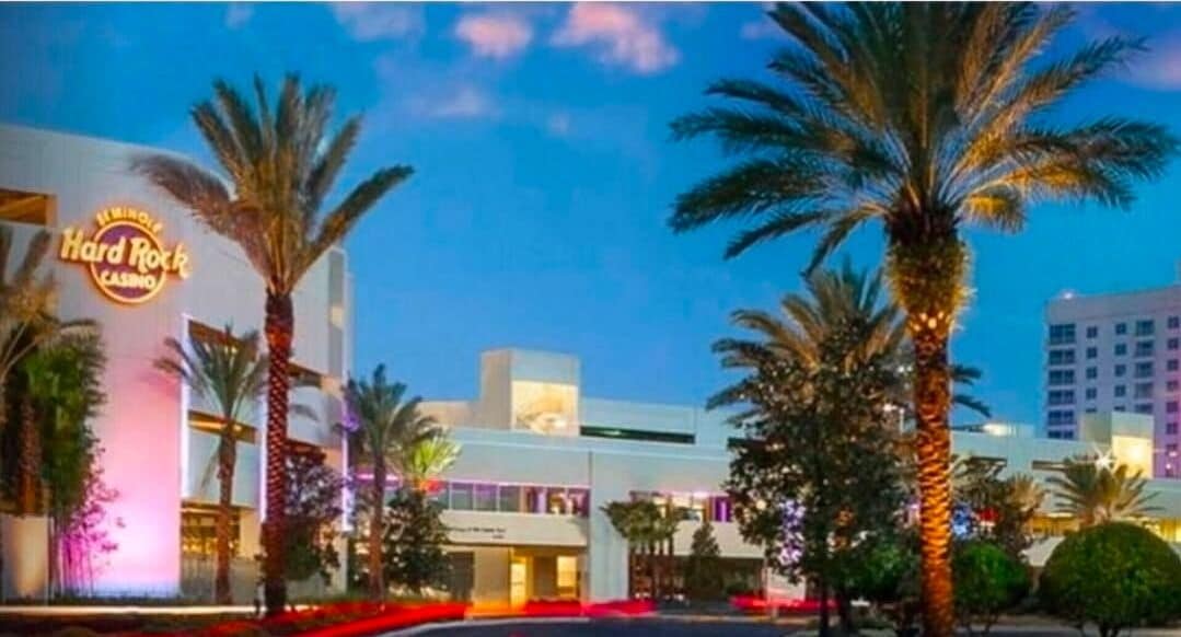 Een Hard Rock Casino met palmbomen, een neonbord en moderne gebouwen.