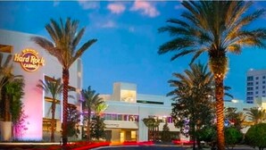 A Hard Rock Casino with palm trees, a neon sign, and modern buildings.