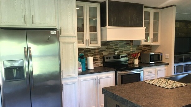 A modern kitchen with stainless steel appliances, white cabinetry, and a granite countertop.