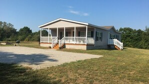 A single-story house with a covered porch, a front staircase, and a well-maintained lawn.