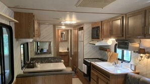 Una cocina compacta para autocaravana con armarios de madera, estufa, pileta y microondas.