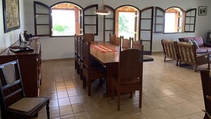 Un comedor con una mesa y sillas de madera, un sofá y una pared decorativa con ventanales arqueados.