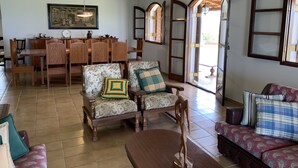 Una sala de estar con comedor, muebles de madera y ventanas de arco.