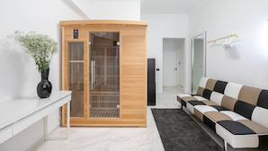 Un salon moderne avec un meuble en bois, une armoire à portes vitrées, un vase noir orné de fleurs blanches et un canapé à motifs.