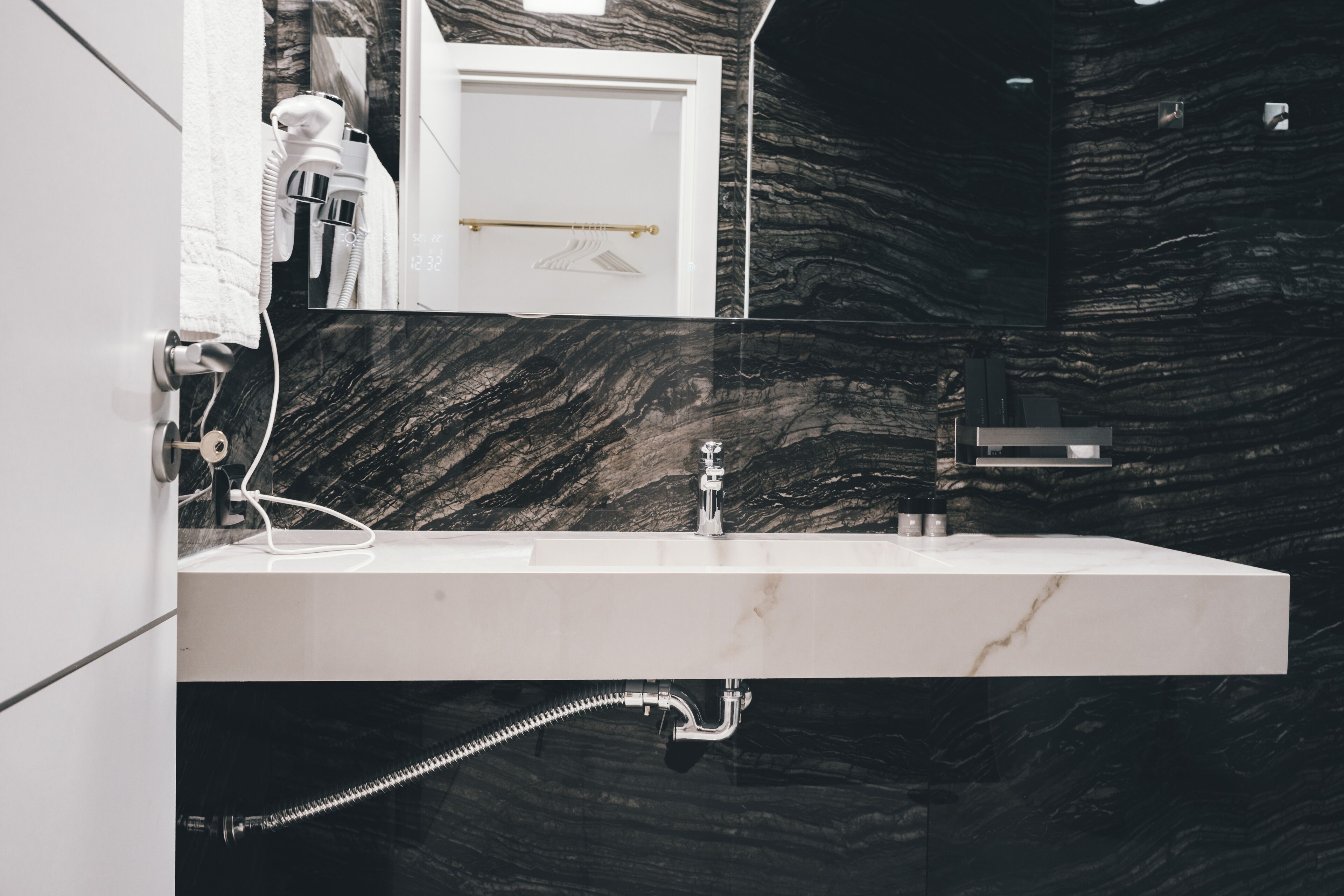 A modern bathroom with a marble sink, a towel rack, and a mirror.