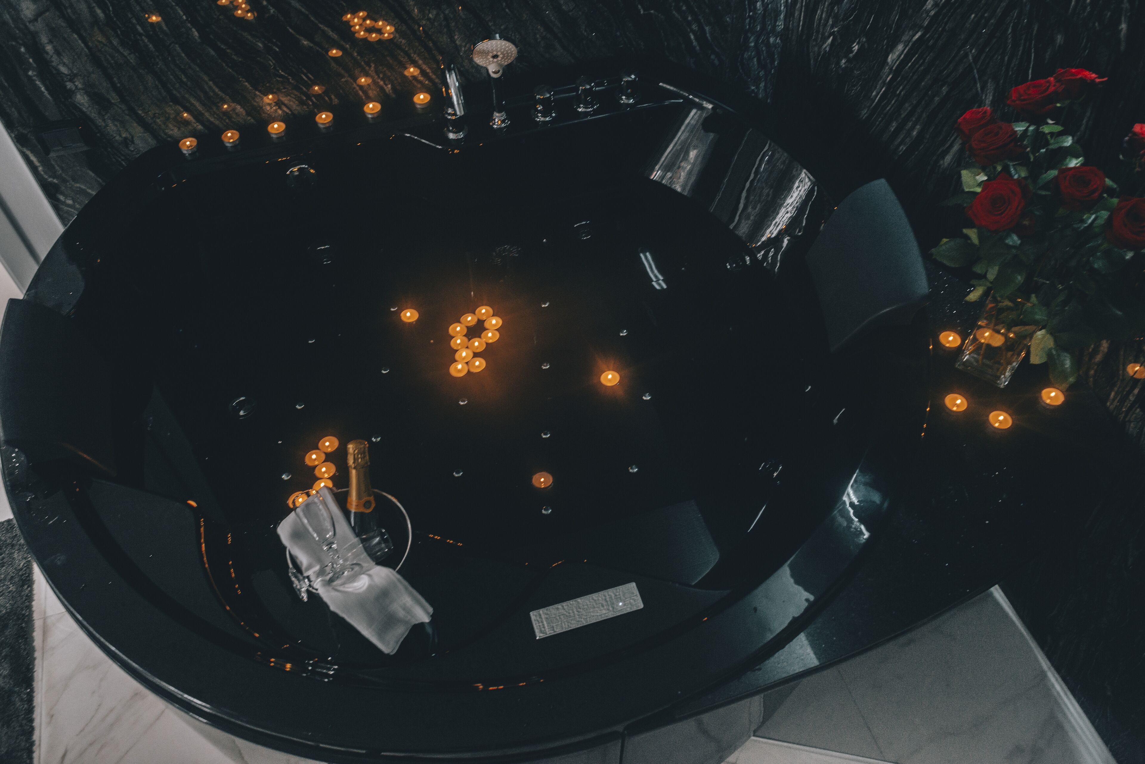 Un espace de détente circulaire avec une table noire, des bougies et un vase rempli de roses rouges.