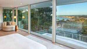 A modern bedroom with a large bed, a round seating area, and a balcony with a view of the coastline. - Single Level Home with 2 Primary Bedrooms, Views and Spa in La Jolla Hills (La Jolla)