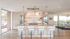 A modern kitchen with a central island, bar stools, pendant lighting, and a view of the outdoors. - Single Level Home with 2 Primary Bedrooms, Views and Spa in La Jolla Hills (La Jolla)