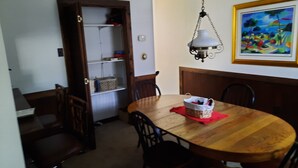 Un comedor con una mesa de madera, sillas, una lámpara colgante y un cuadro en la pared.