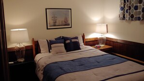 Habitación de hotel con cama, dos mesitas de noche con lámparas, un cuadro enmarcado en la pared y una cortina estampada.