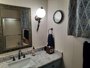 Une salle de bain équipée d’un lavabo, d’un miroir, d’un porte-serviettes et d’une horloge murale.