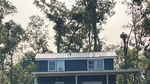 Uma casa de dois andares com um deck de madeira, um escorrega e uma pilha de lenha.