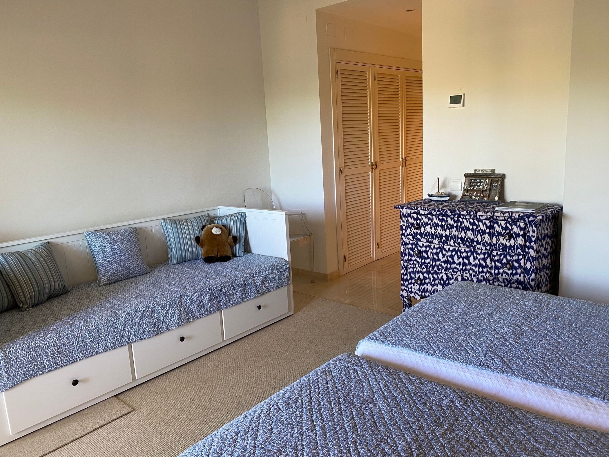 A bedroom with a sofa bed, a small table with a decorative item, and a wardrobe.