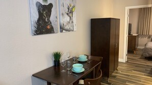 Un comedor con una mesa dispuesta para dos personas, una planta en maceta y dos cuadros abstractos en la pared.