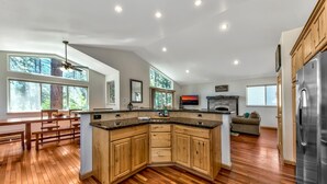 Une cuisine moderne avec des meubles en bois, un grand îlot central et un réfrigérateur encastré.