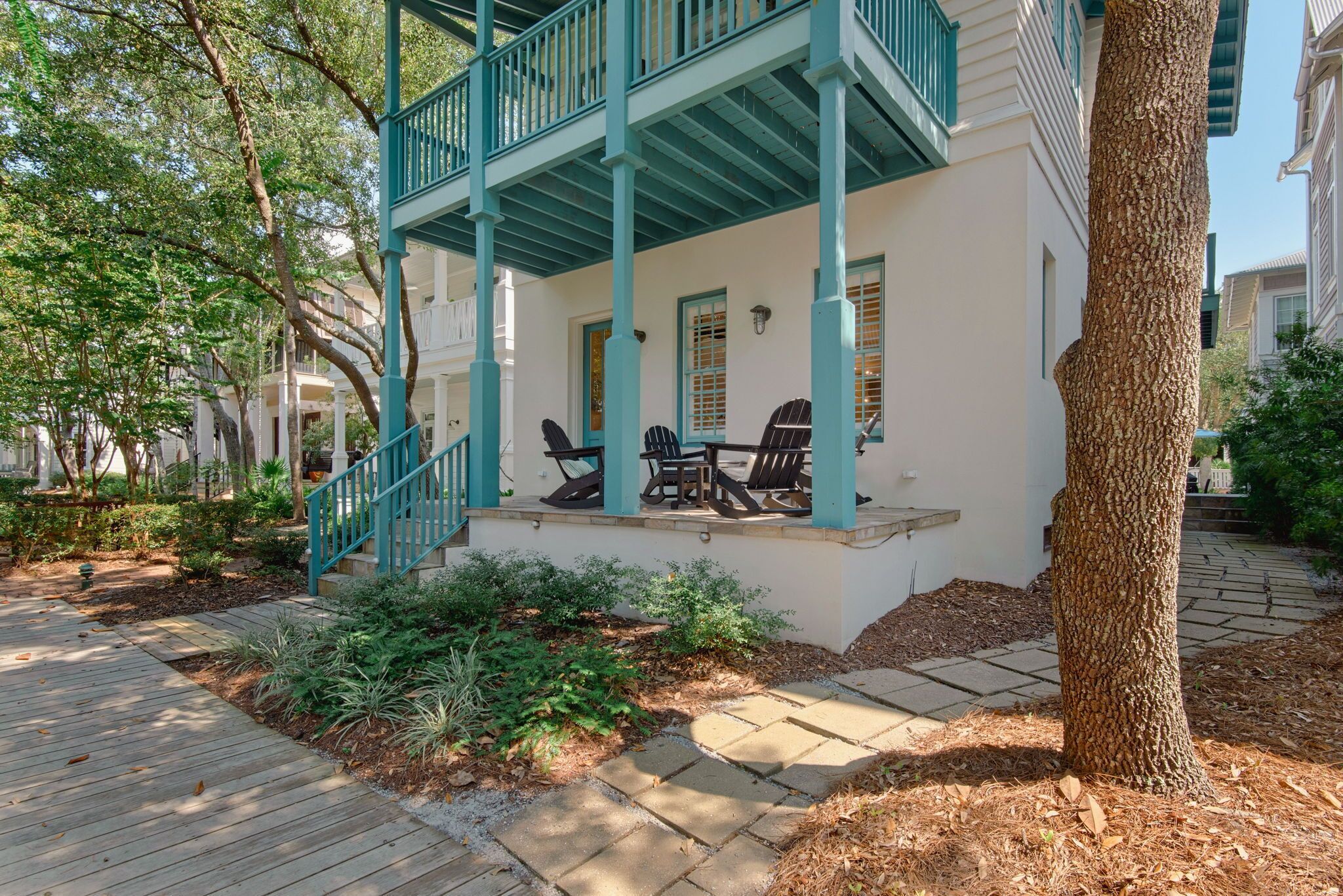 A white building with teal railings and a covered porch with outdoor seating.