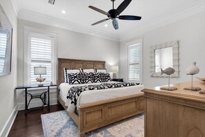 Une chambre à coucher comprenant un lit, une table de chevet, une lampe, une commode et un ventilateur de plafond.