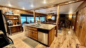 A spacious kitchen with wooden cabinets, a granite countertop, and a dishwasher. - Pine View Cabin: Rustic Hayden Lake Cabin with Bunkhouse and Private Dock (Hayden)
