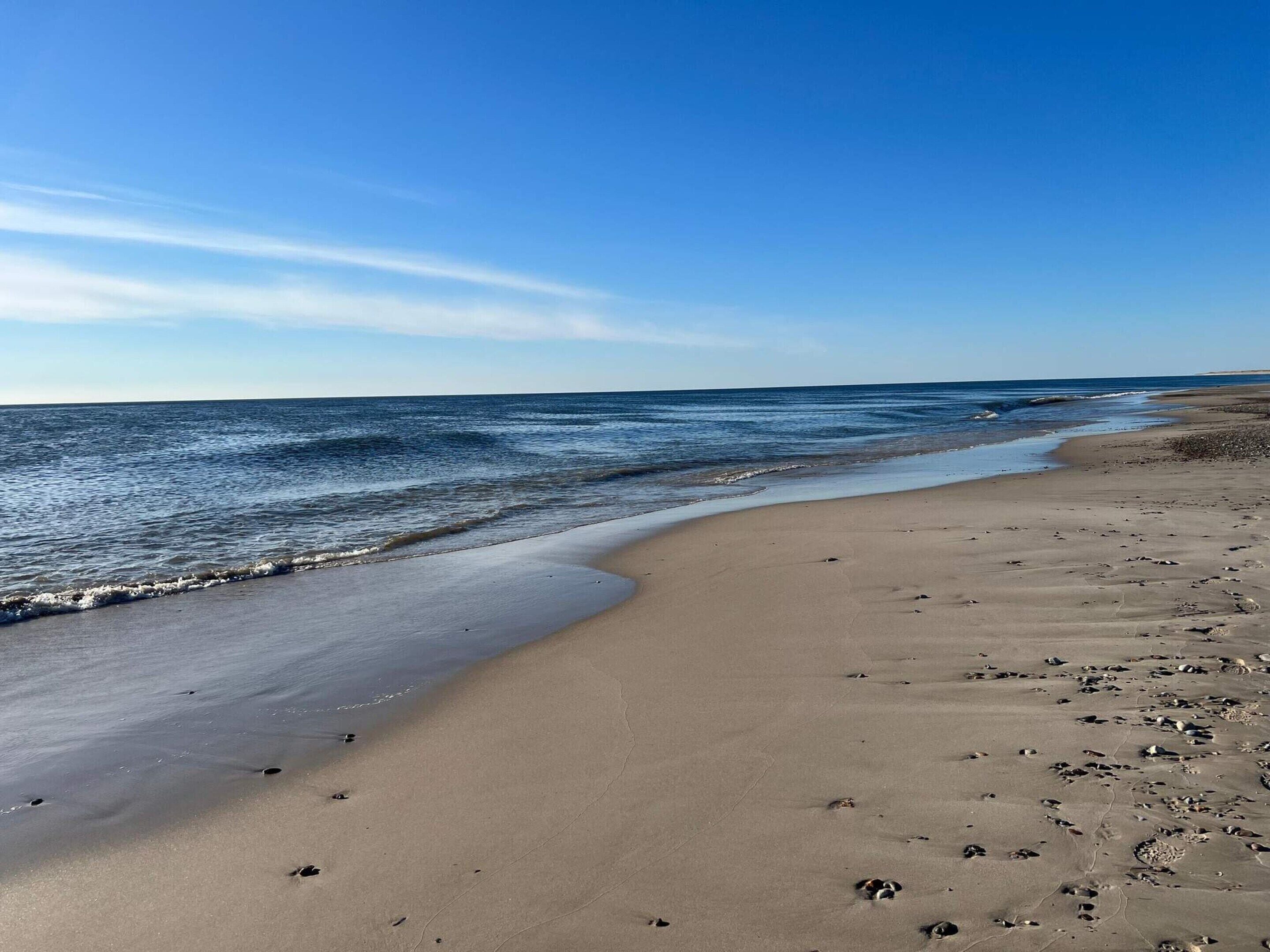 A beach with a sandy shore and footprints.