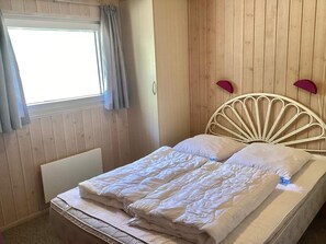 A room with a bed, a window with curtains, and a wooden wall. - Holiday Home in NÃ¸rre Nebel (Norre Nebel)