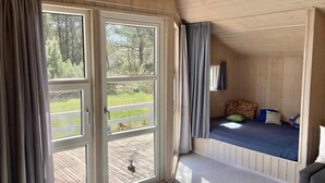 Una habitació amb llit, finestra i vista a una terrassa.