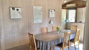 Zona de menjador amb taula de fusta, cadires i obra d'art a les parets.