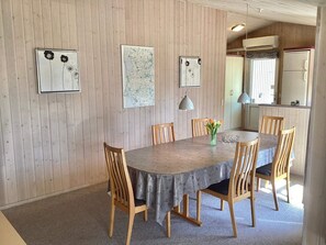 A dining area with a wooden table, chairs, and artwork on the walls. - Holiday Home in NÃ¸rre Nebel (Norre Nebel)