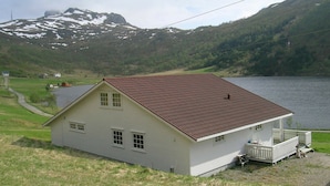 A white house with a red roof, a dock, and a lake in the background. - Holiday Home in Leknes (Vestvågøy)