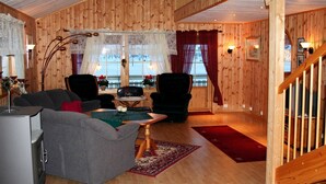 A cozy wooden interior with a sofa, chairs, a table, and a staircase. - Holiday Home in Leknes (Vestvågøy)