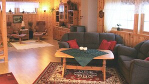 A cozy living room with wooden walls, a sofa, a coffee table, and a fireplace. - Holiday Home in Leknes (Vestvågøy)