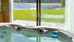 Ein Whirlpool mit Blick auf einen See und eine Wiese durch ein Fenster.