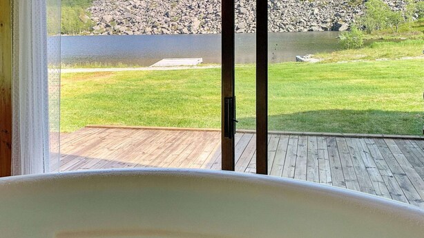 Eine Badewanne mit Blick auf einen Rasen und eine Holzterrasse.