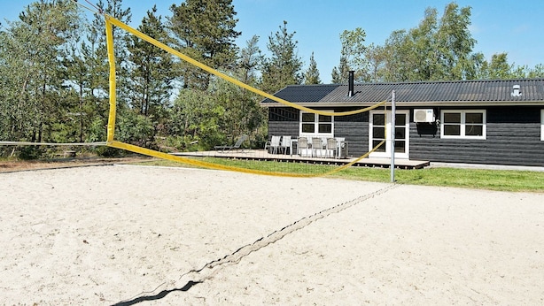 Une cabane dotée d’une véranda, de sièges extérieurs et d’un grand filet de sécurité jaune.