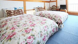 A bedroom with two beds, wooden beams, a television, and a window. - Auberge Meiyanoki (Ikeda)
