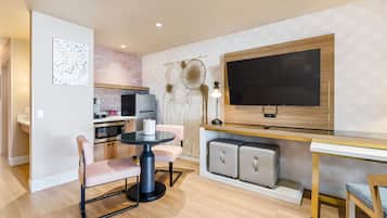 A modern kitchen with a microwave, oven, and sink. There is a dining table with chairs and a small round table with a lamp.