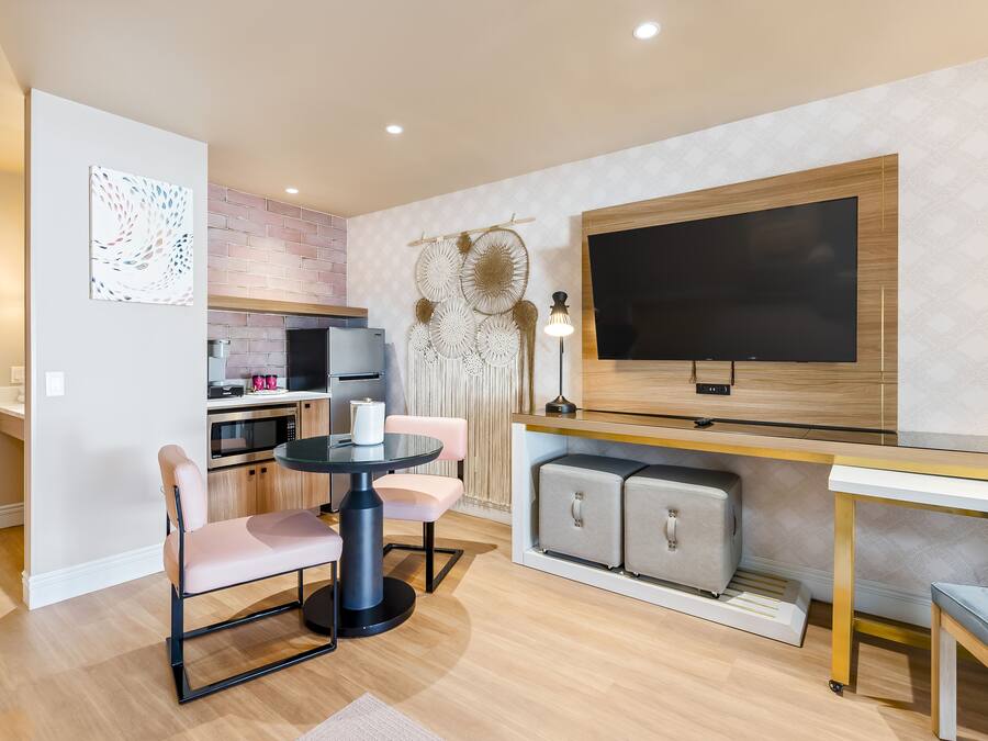 A modern kitchen with a microwave, oven, and sink. There is a dining table with chairs and a small round table with a lamp.