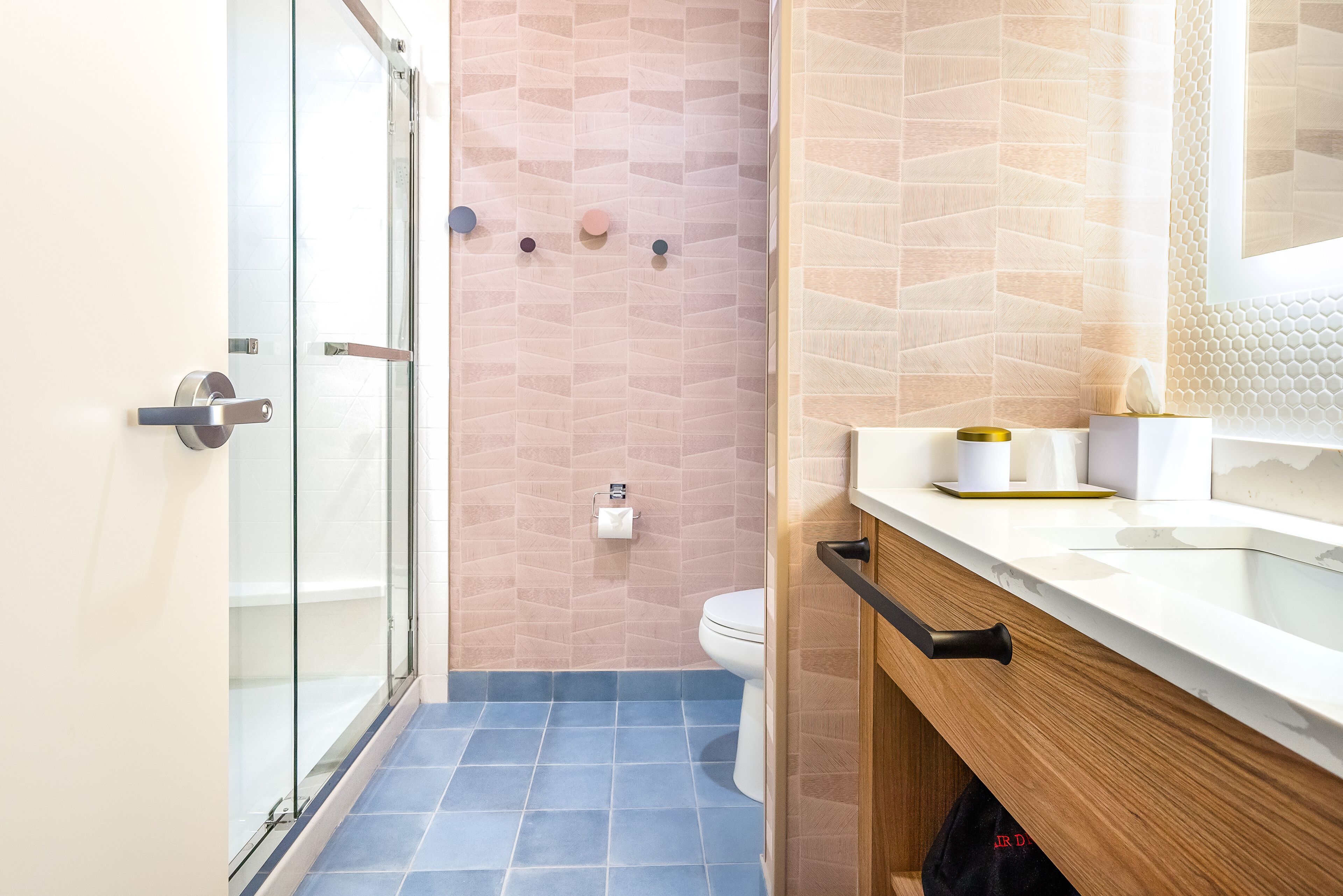 Un baño moderno con cabina de ducha de vidrio, inodoro y tocador con lavamanos y espejo.