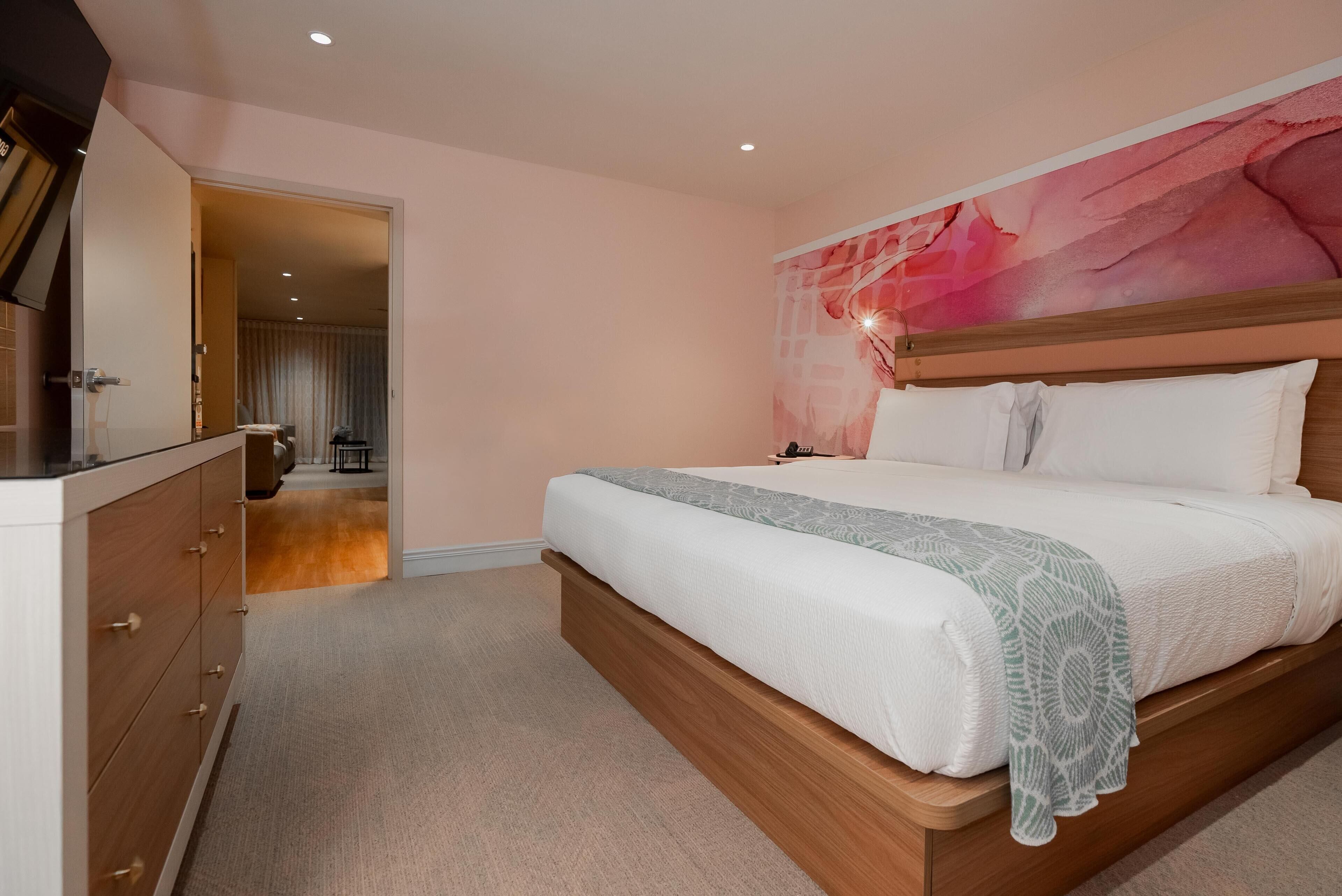 A bedroom with a bed, wooden headboard, and a wall mural.