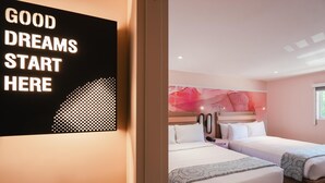 A hotel room with two beds, a wall art piece with the text "GOOD DREAMS START HERE", and a pink abstract wall design. - The Bentley Hotel Southampton (Southampton)