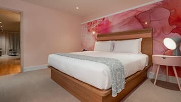 A modern bedroom with a large bed, a nightstand, and a wall mural.
