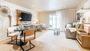 A modern living room with a flat-screen TV, a dining area with a round table and chairs, a sofa with cushions, and a small side table with a lamp. - The Bentley Hotel Southampton (Southampton)