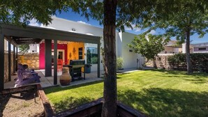 Een modern huis met een overdekte patio, buitenmeubels en een verzorgd gazon.