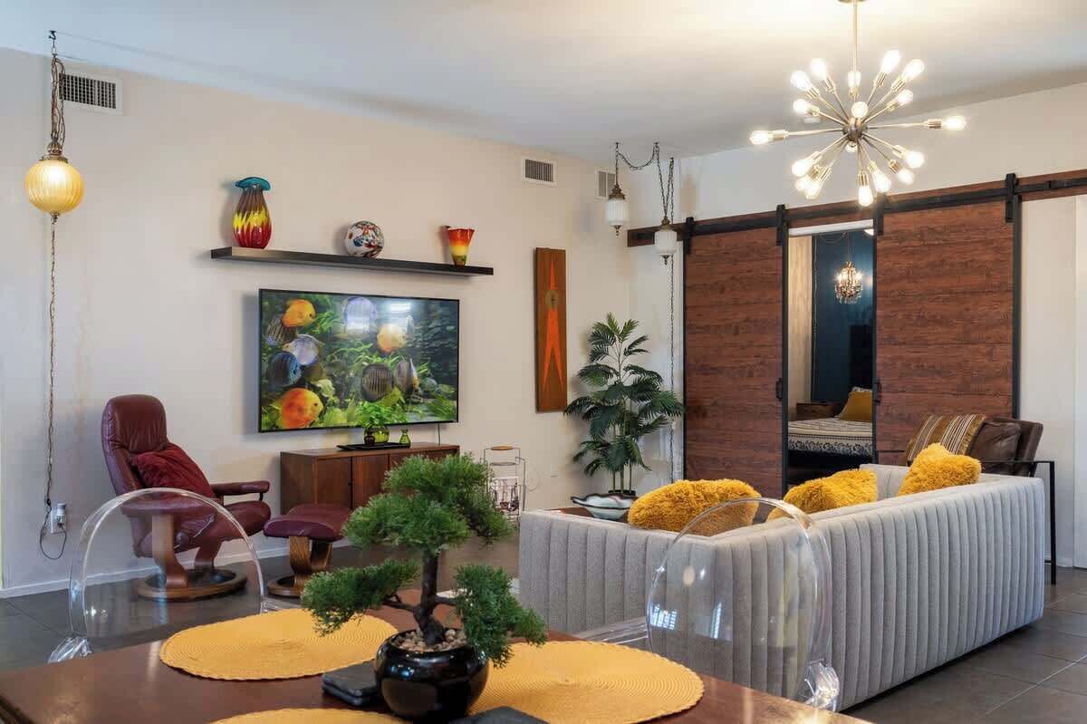 A modern living room with a television, sofa, and decorative plants.
