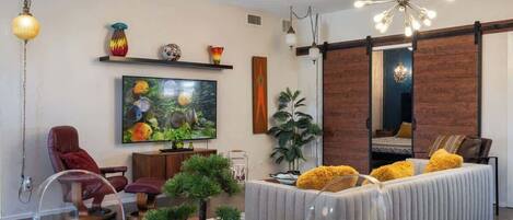A modern living room with a television, sofa, and decorative plants.
